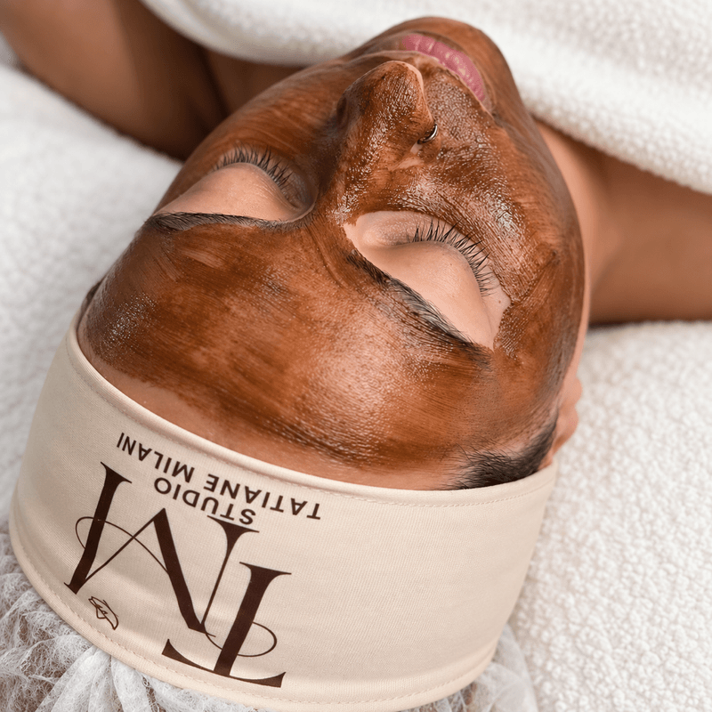 Cliente relaxando com máscara facial e faixa do Studio Tatiane Milani